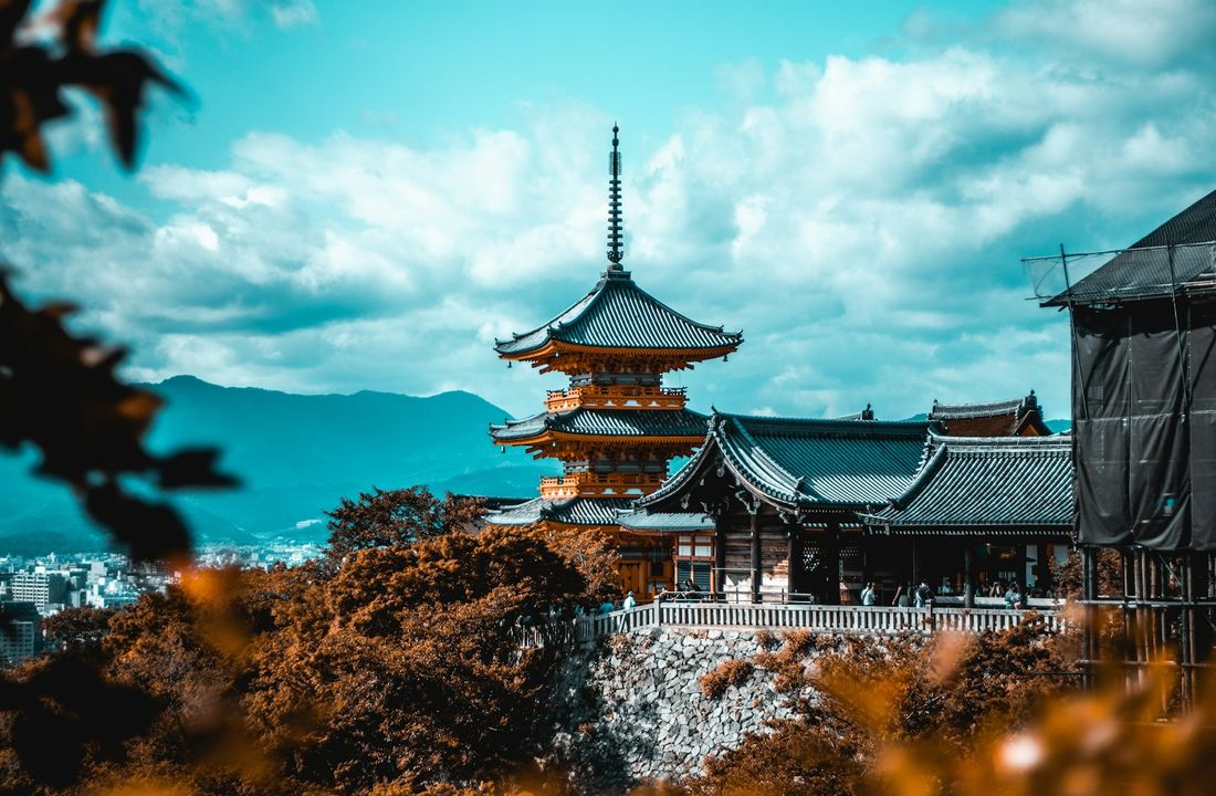 The pagoda of Kiyomizu-dera above red and orange maples on a clear autumn day