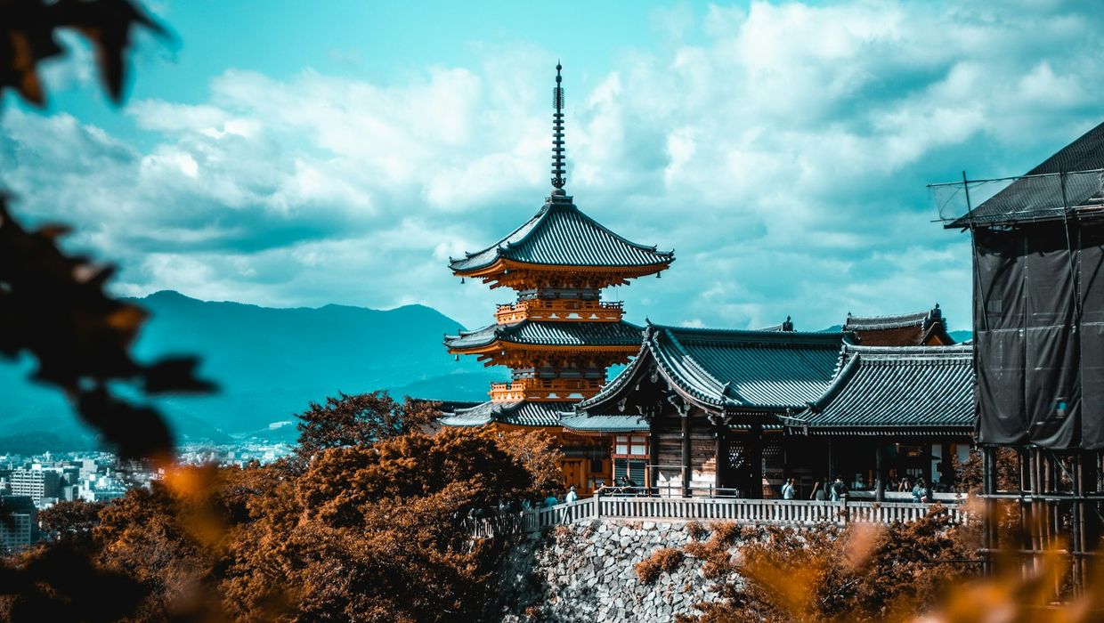 The pagoda of Kiyomizu-dera above red and orange maples on a clear autumn day