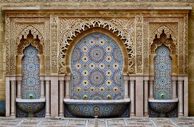 A tiled fountain framed by carved plaster arches in the courtyard of a Marrakech riad
